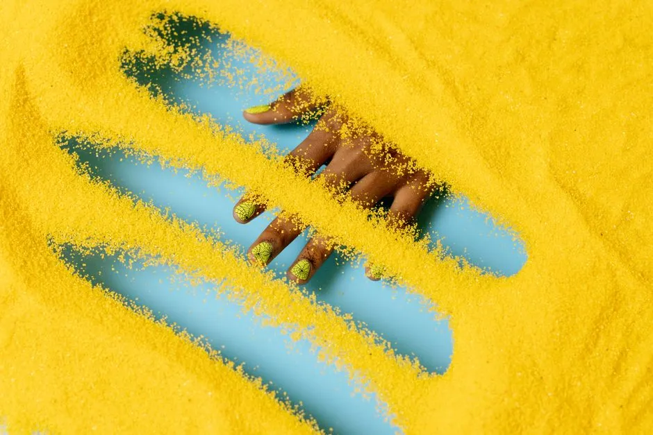 A hand being dipped into colored powder during a dip powder manicure